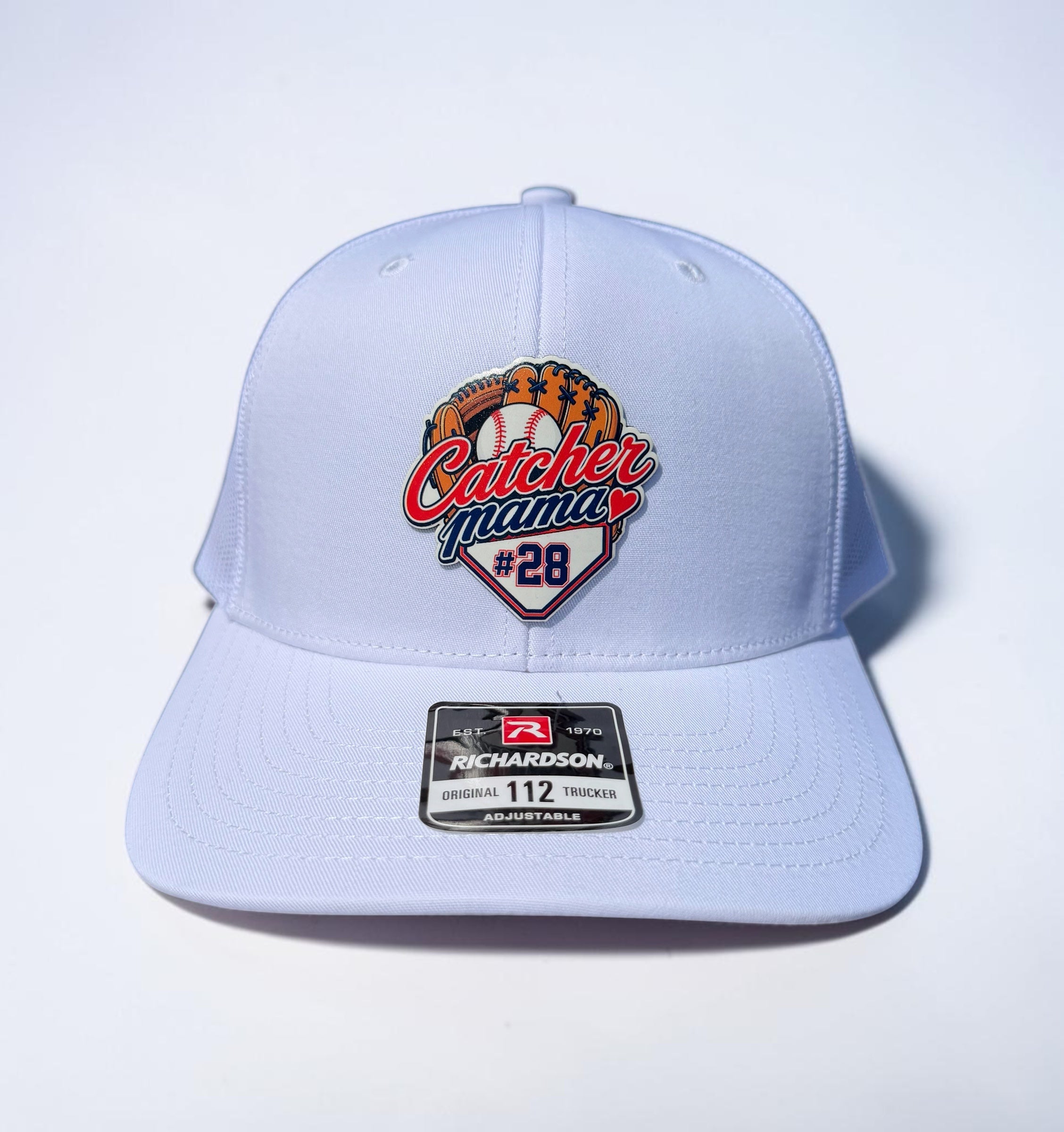 White structured baseball cap with a front patch reading 'Catcher Mama #28' and a Richardson 112 sticker on the brim, photographed on a clean white 